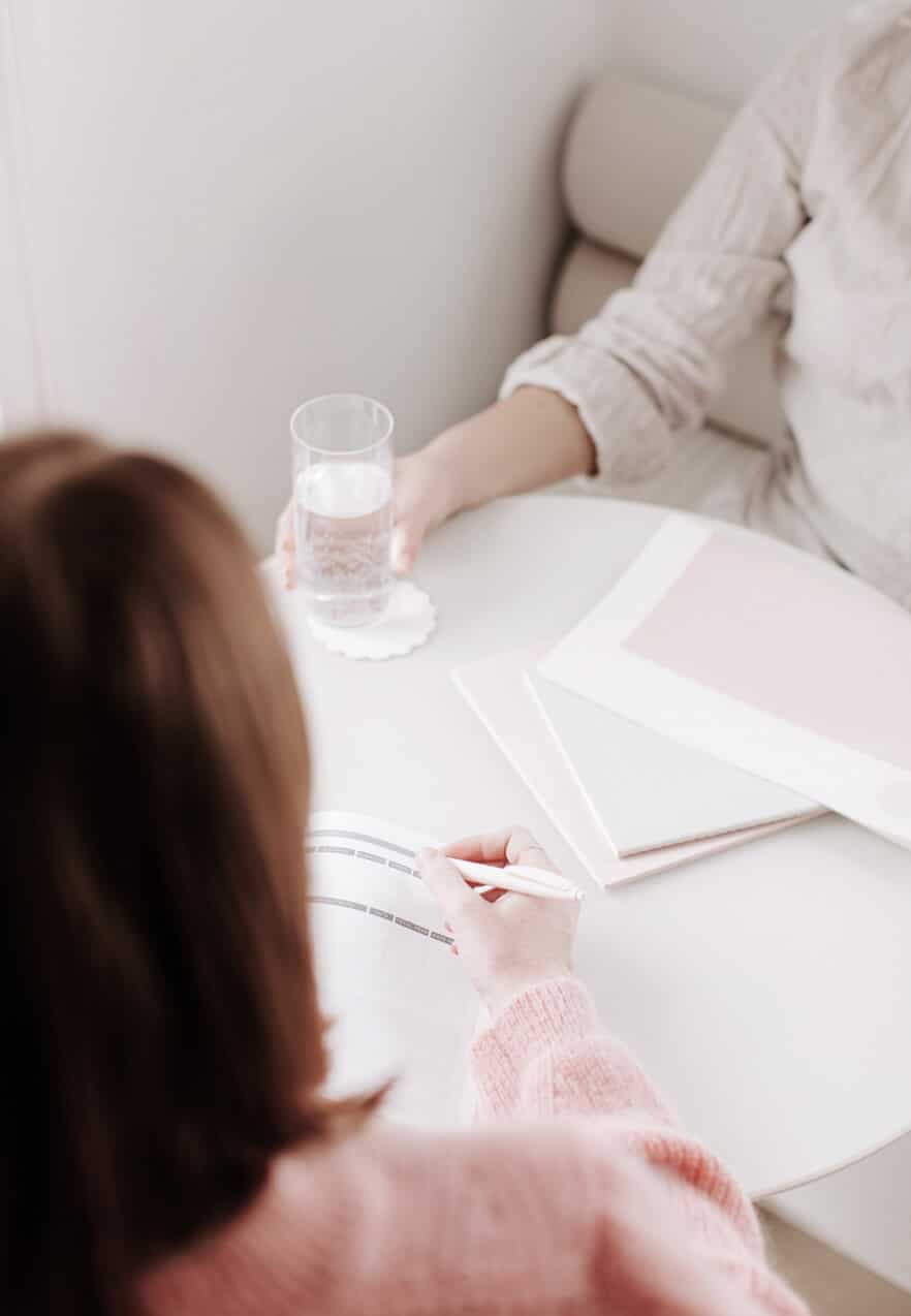 Two people sitting at a round table with preparation paperwork in front of them.